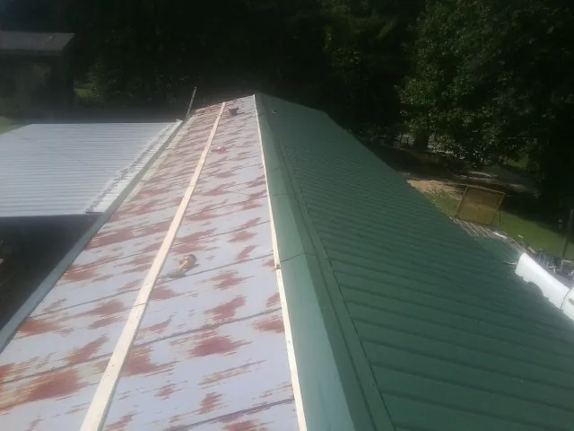 Old rusted panels beside newly installed green metal roofing — Wind Damage Roof Repair by Roofing Brothers in Hazlet