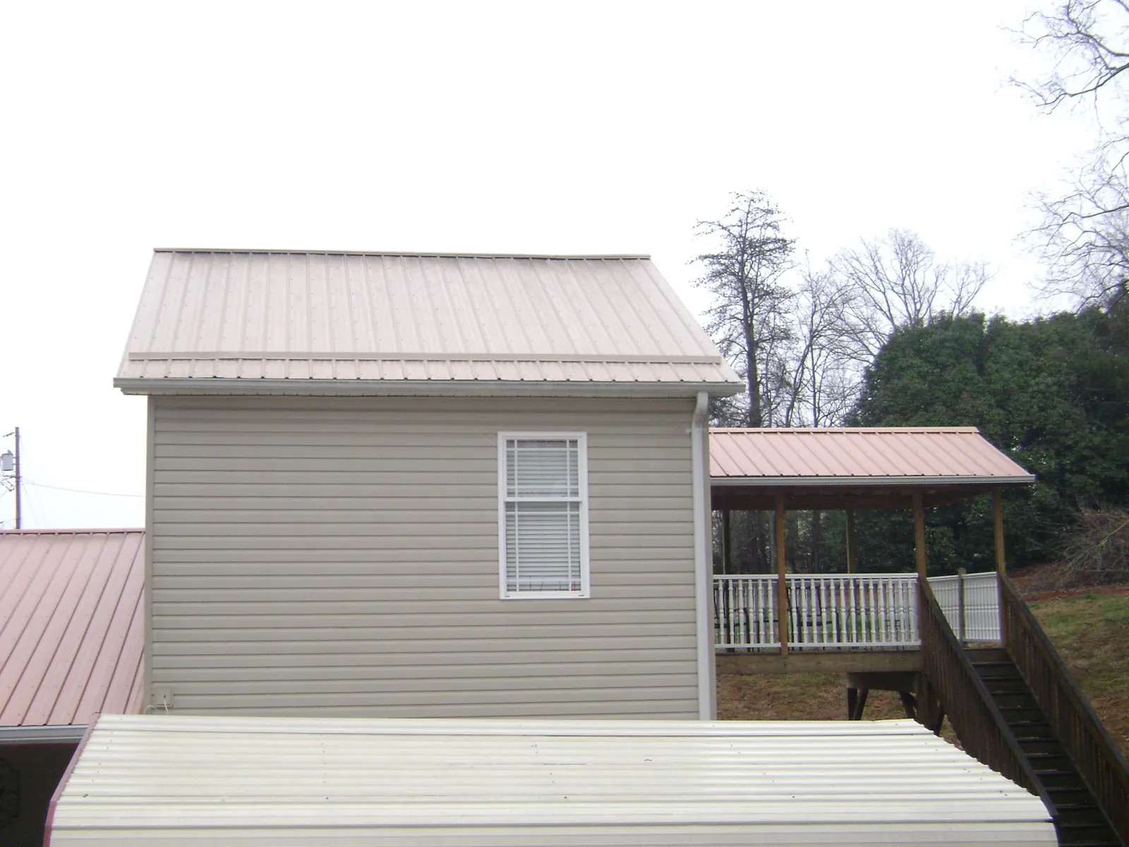 Tan metal roofs on a two story addition and attached porch, from a Roof Replacement job in Hazlet
