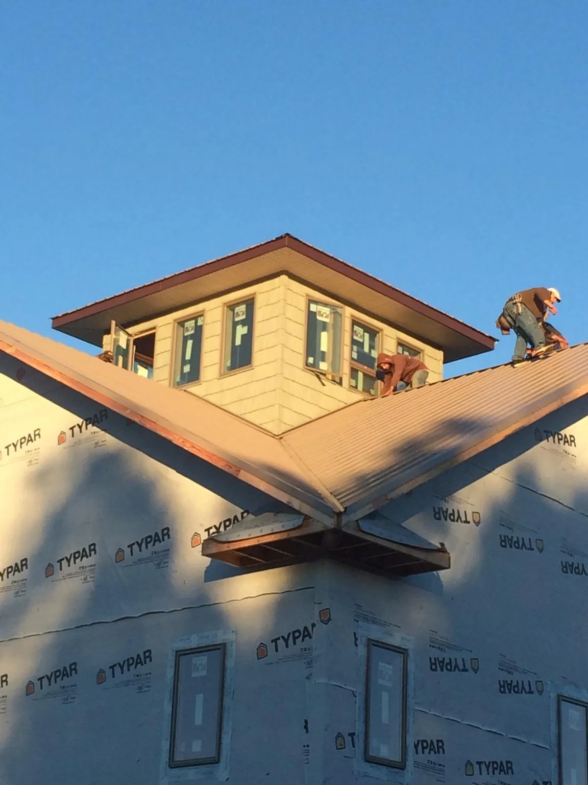 Roofers working around a rooftop cupola on a new metal roof at sunset — Roof Waterproofing in Hazlet by Roofing Brothers